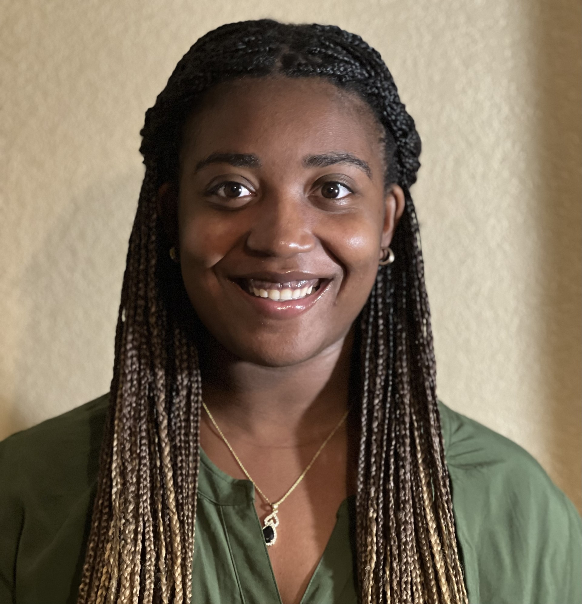 A person with braided hair smilingDescription automatically generated with low confidence